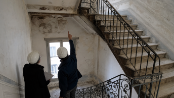 Deux ouvriers casqués pointant un escalier en fer