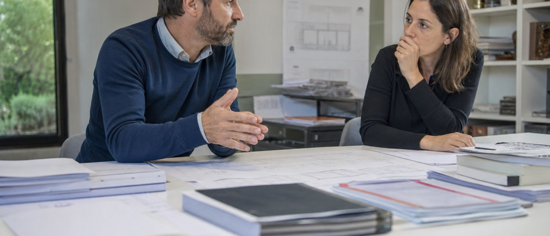 Deux collègues discutent de plans posés sur la table