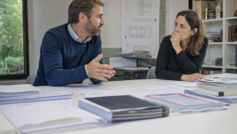 Deux collègues discutent de plans posés sur la table